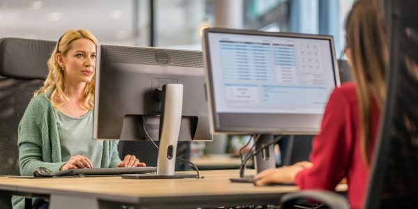 Customer service representative working on desktop computer in call centre.